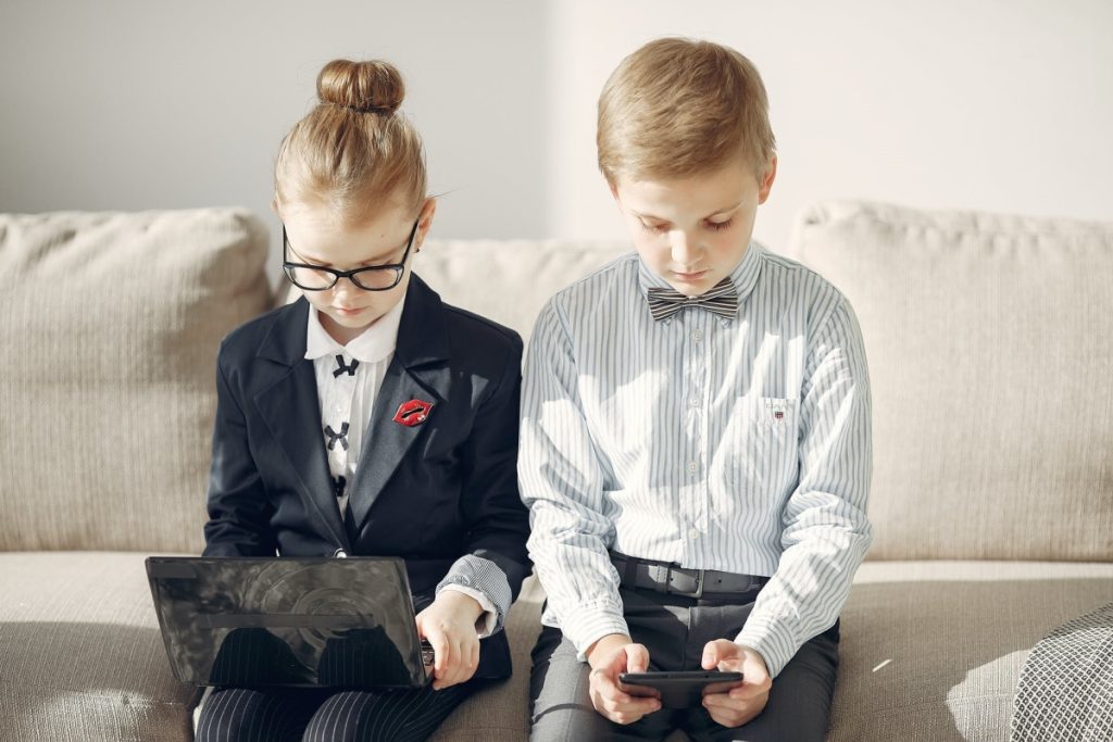 bambini sul divano con telefono e computer